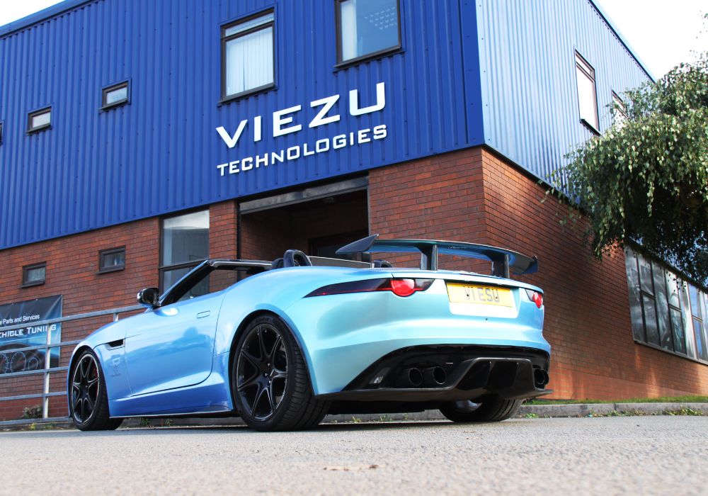 A blue sports car parked in front of a building jaguar f-type